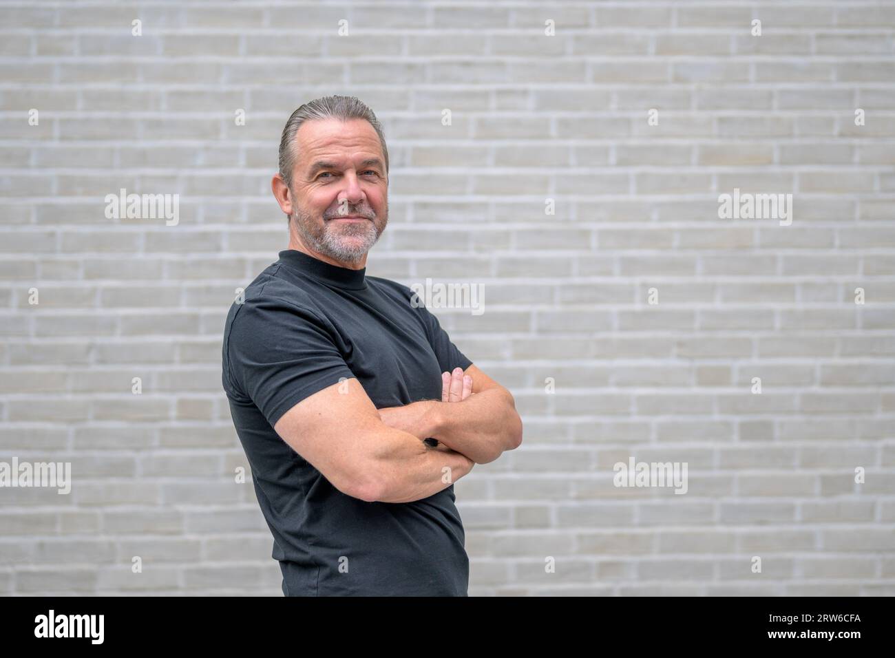 Side view of an attractive man with crossed arms looking to the camera ...