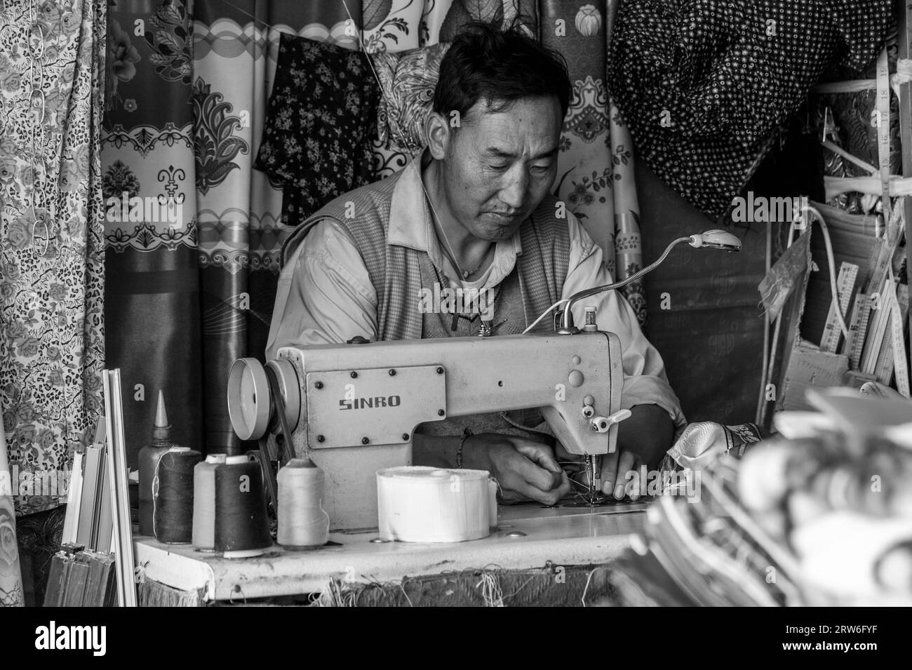GYANTSE, TIBET, CHINA - AUGUST, 21 2018: Unidentified tibetan man with sewing machine in Gyantse, Gyantse Country, Shigatse, Tibet Stock Photo
