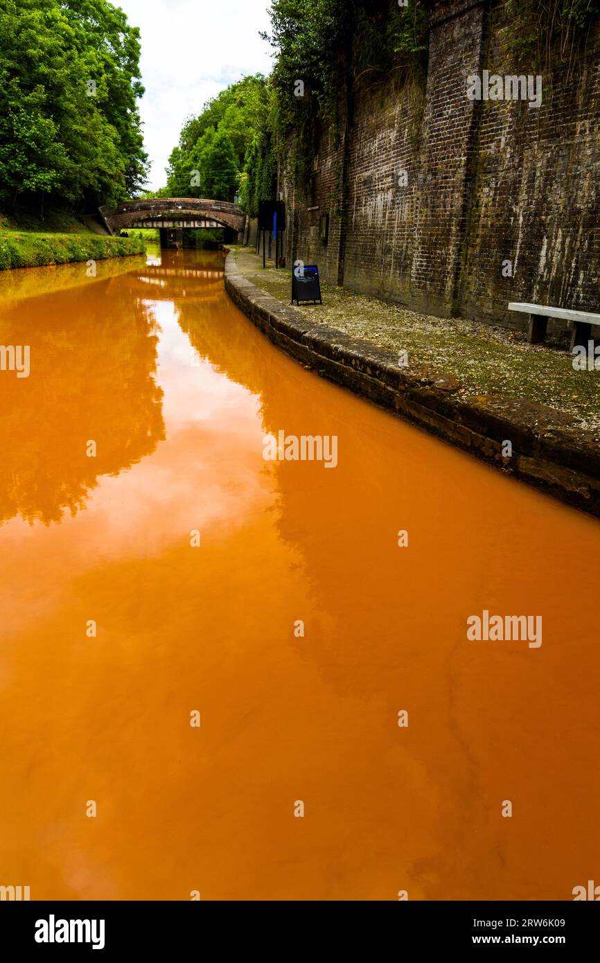 The Trent and Mersey Canal, Kidsgrove, Newcastle-under-Lyme. The water is orange because if clay deposited in the Harecastle Tunnel, portrait, wide an Stock Photo