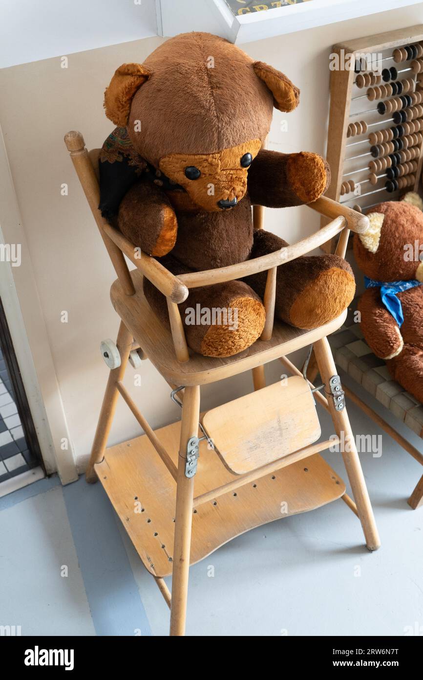 Old toy bear. Wooden high chair for children and baby. Ragdoll. Vintage teddy bear. Stock Photo