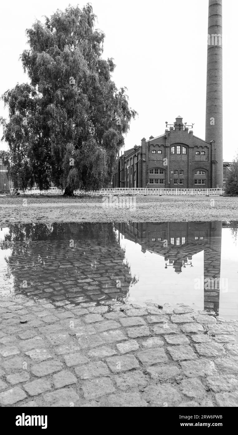 Old train factory building with reflection on a puddle Stock Photo