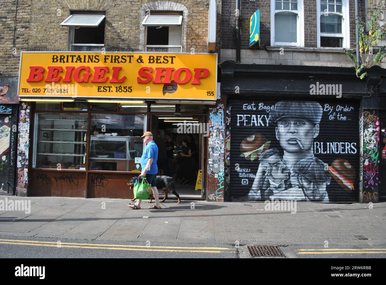 Image of Brick Lane featuring the world famous bagel shop established in 1855 and some street art of Peaky Blinders on the shutters next door. Stock Photo