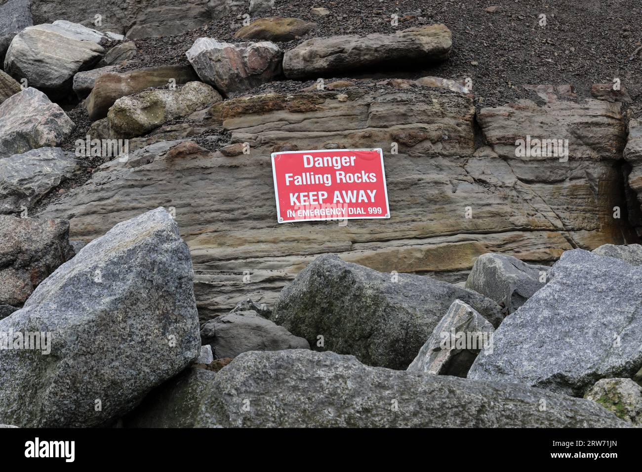 Danger Falling Rocks Sign on the Beach at Staithes, North Yorkshire, UK Stock Photo