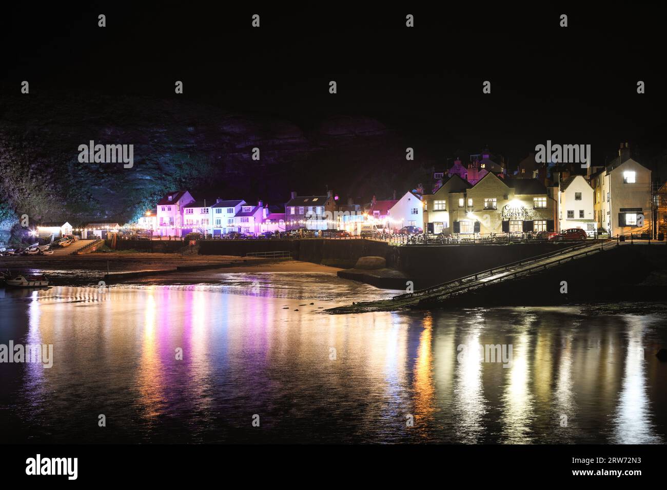 Staithes Harbour at Night Illuminated with Colourful Lighting During the Staithes Festival of Arts and Heritage, North Yorkshire, UK Stock Photo