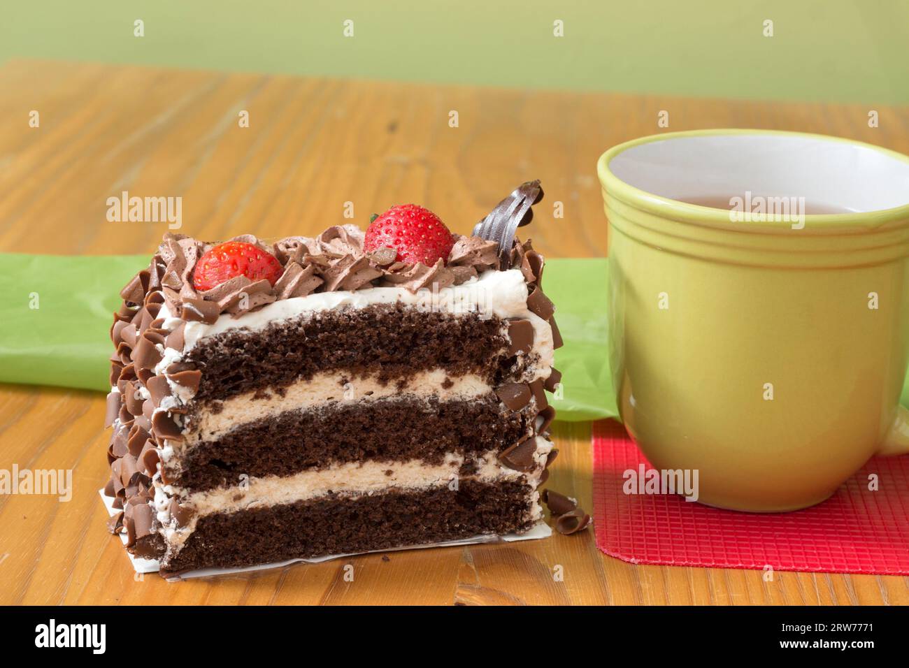 A large slice of chocolate layer cake with cream and hot drink Stock Photo