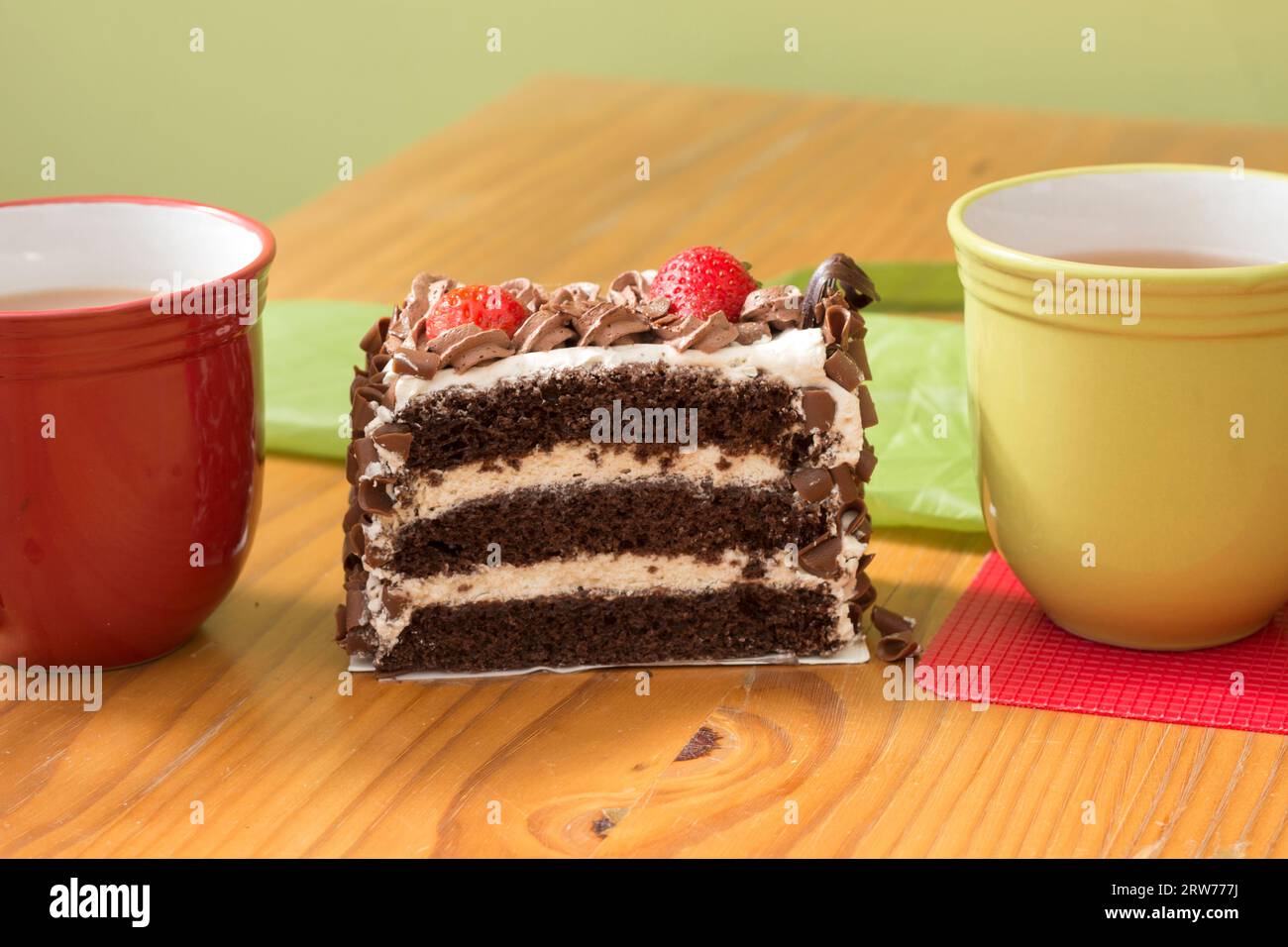 Cups of tea and coffee with a large slice of layer cake at an event Stock Photo