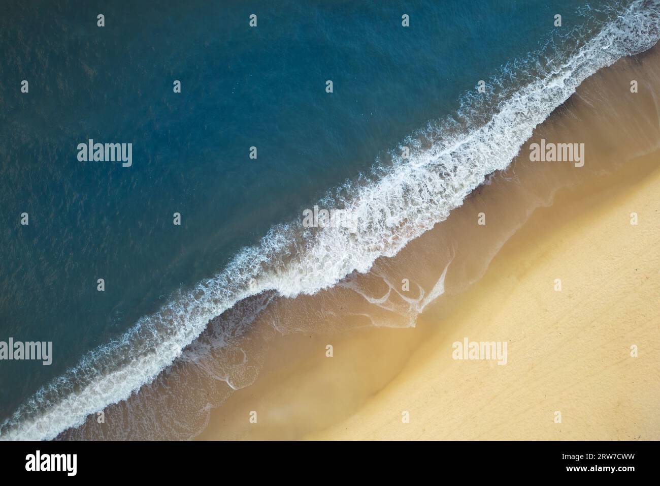 Aerial view of Baltic Sea shoreline with waves crushing sand beach during sunrise in the morning, bird's perspective, top down view, drone photography Stock Photo