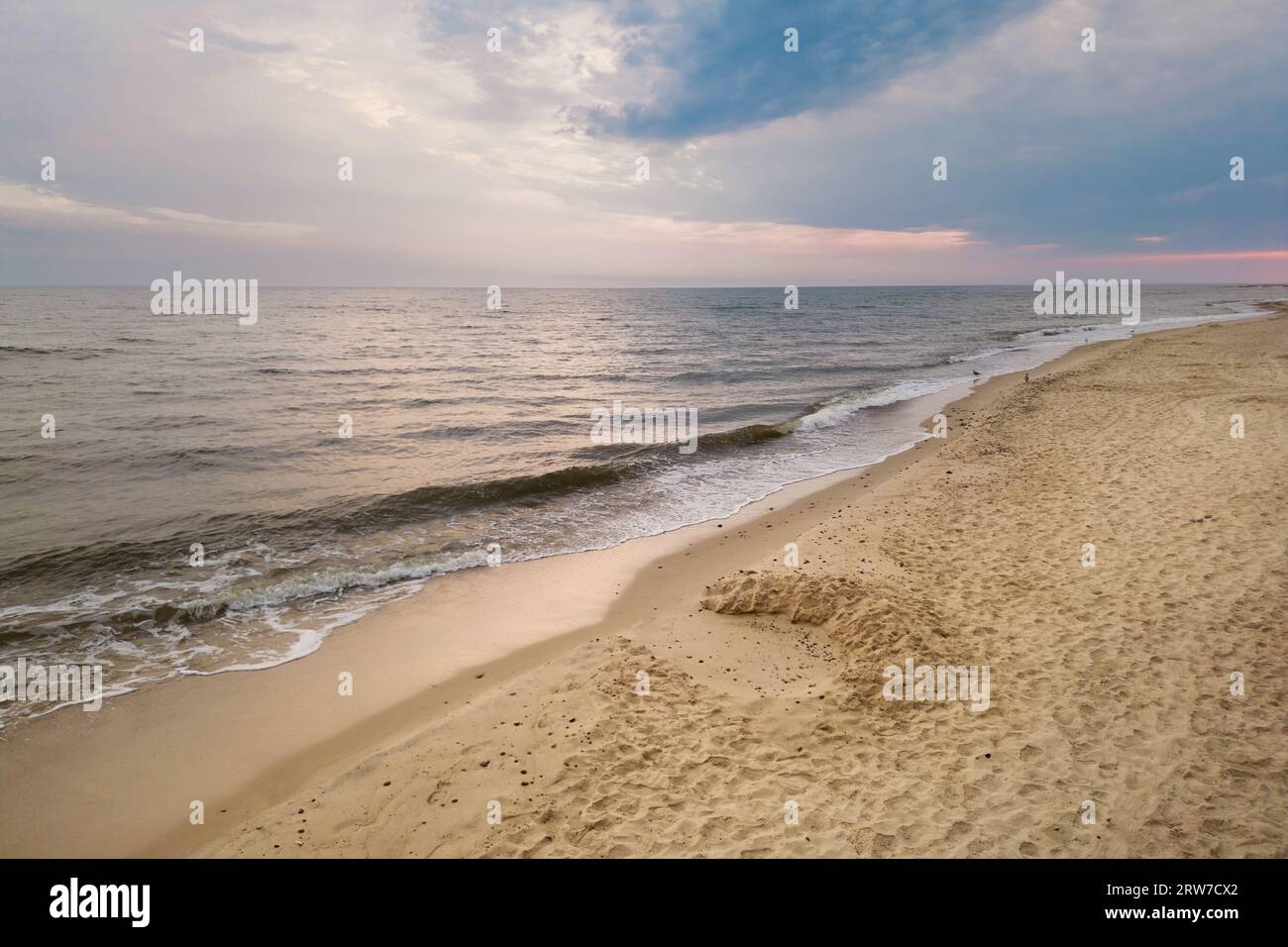 Aerial view of Baltic Sea shoreline with waves crushing sand beach during sunrise in the morning, bird's perspective, drone photography Stock Photo