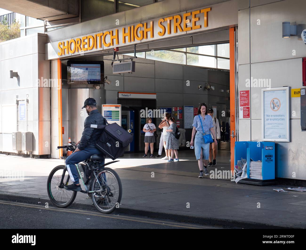 Shoreditch High Street TFL overground station, London, with cyclist  and commuters leaving the exit Stock Photo