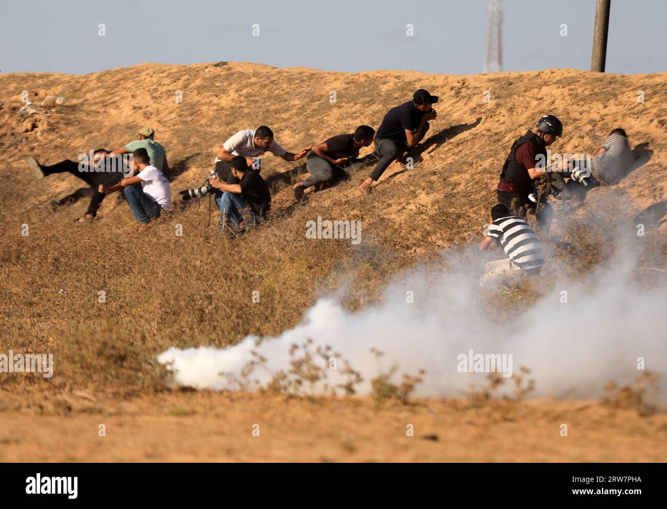 Palestinian demonstrators flee from tear gas bombs fired by Israeli security forces along the border with Israel, east of Khan Yunis, in the southern Gaza Strip. Stock Photo