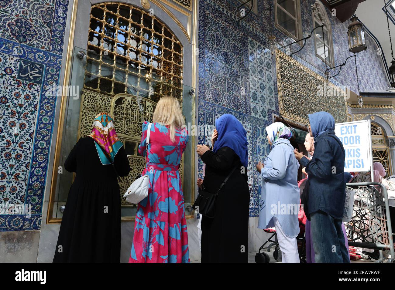 Muslim women praying in front of the tiled wall of the Eyüp Sultan tomb at the Eyüp Sultan Mosque in Istanbul, Turkey Stock Photo
