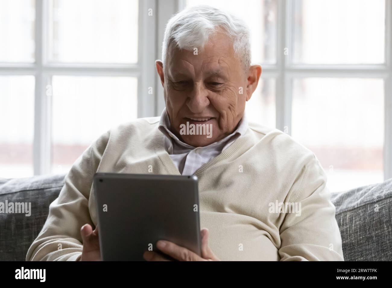 Modern elderly man using tablet at home Stock Photo