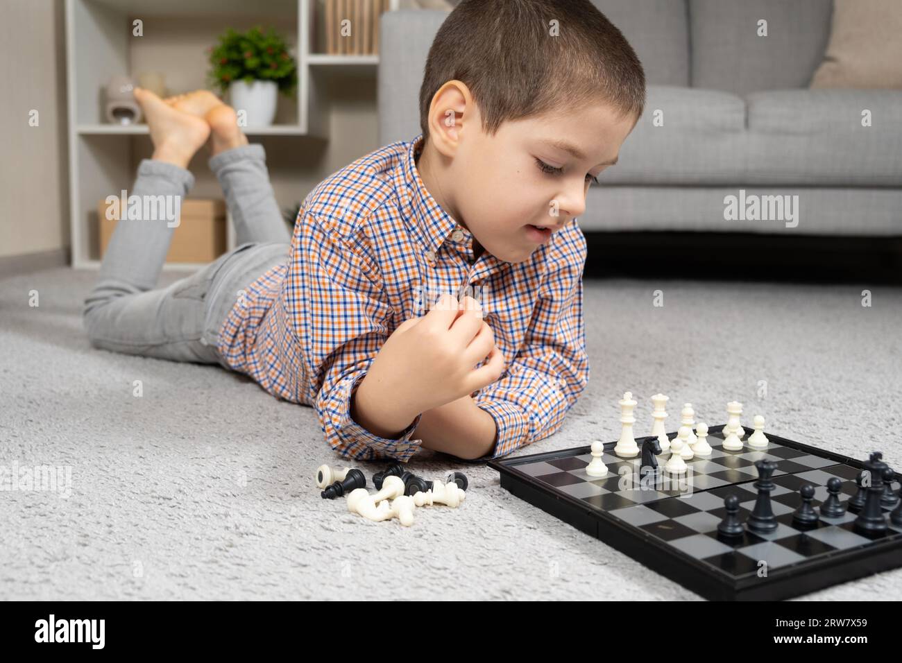 Pupil kid thinking about his next move in a game of chess. Concentrated  little boy sitting at the table and playing chess Stock Photo - Alamy