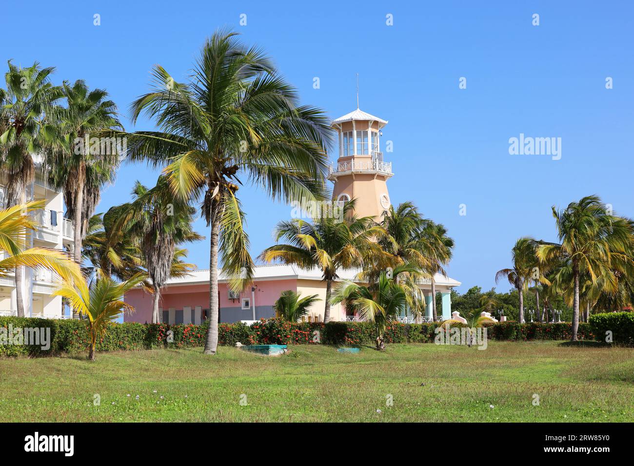 Tropical resort, palm trees on villa buildings and lighthouse background. Holidays on paradise nature of Caribbean islands Stock Photo