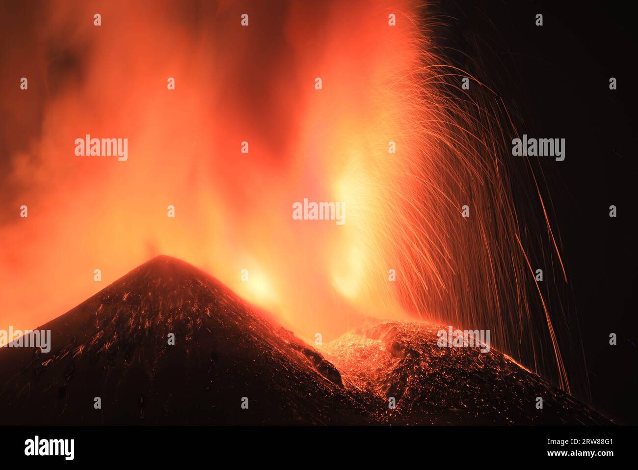 Etna - Esplosione di lava intensa  sul vulcano etna dal cratere  durante un eruzione vista di notte con silhouette del cratere in controluce Stock Photo