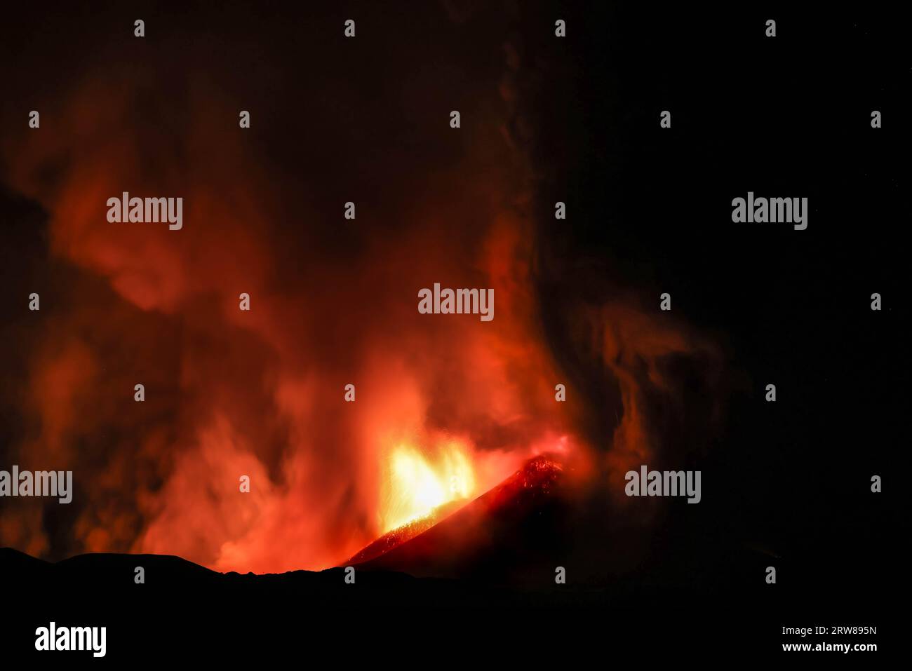 Etna durante suggestiva eruzione di notte dal cratere del vulcano con volti e forme immaginarie creati dalle emissioni di fumo. Agosto 2023 Stock Photo