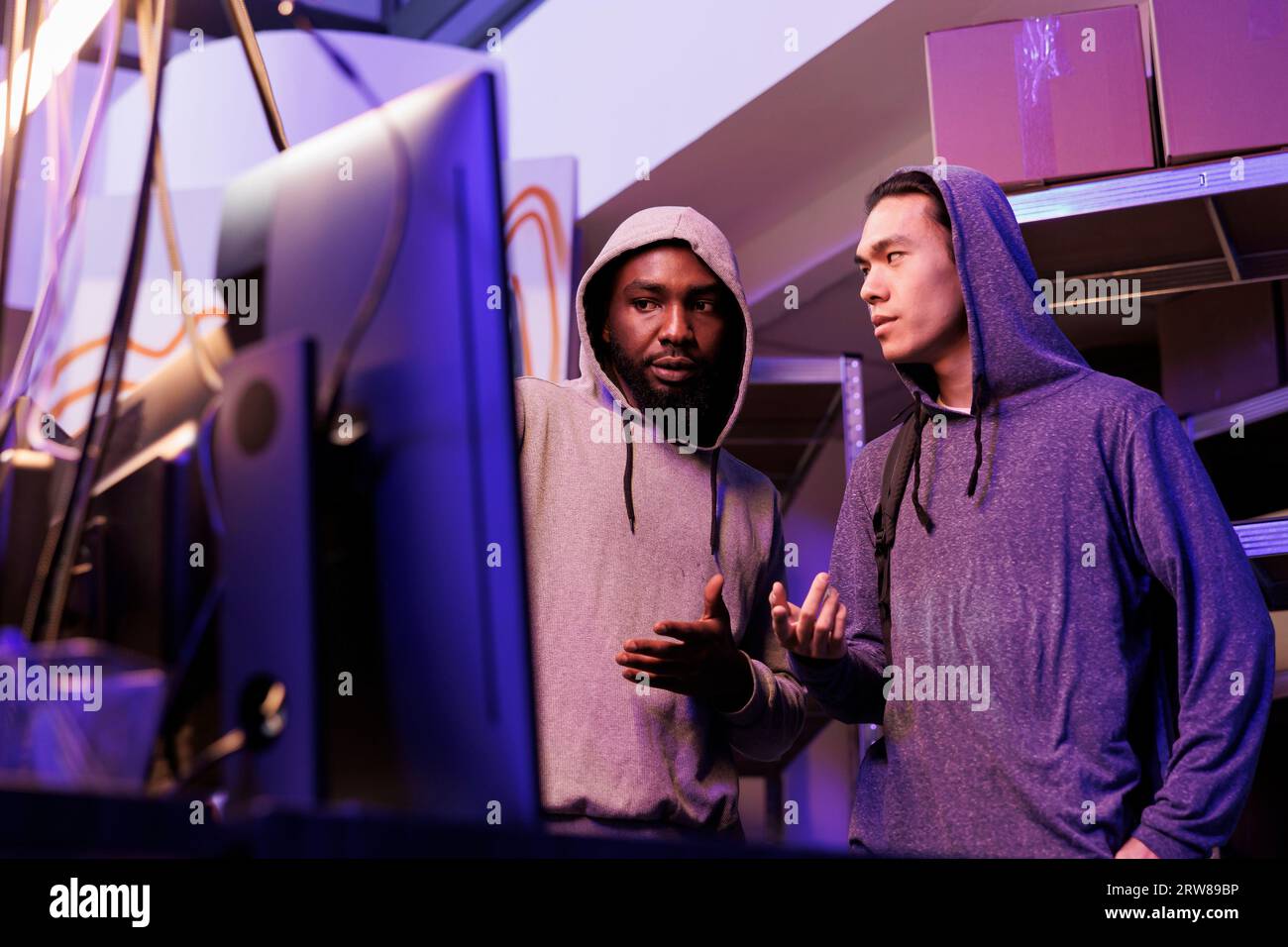 Hackers discussing malware code while looking at computer screen. Two ...