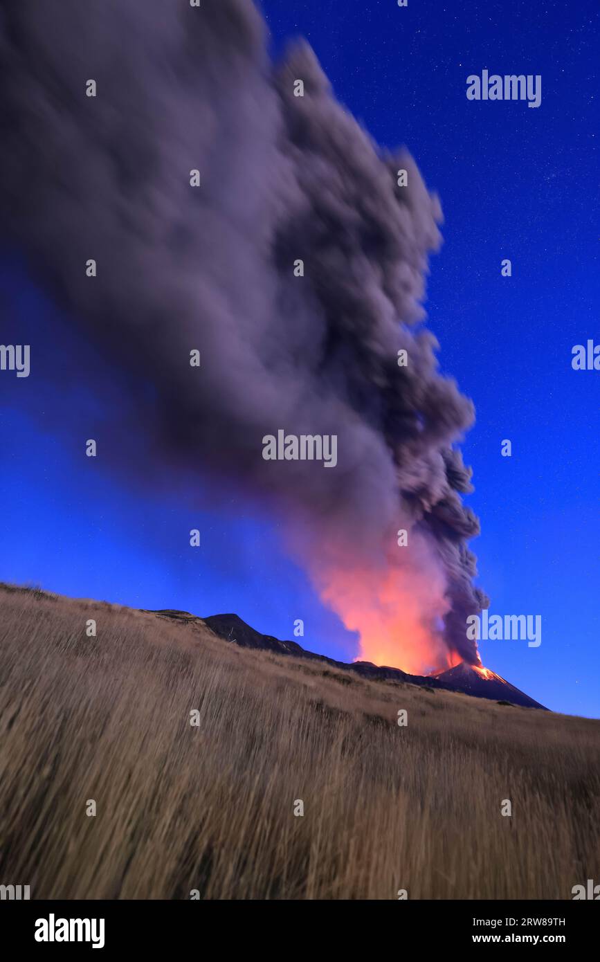 Eruzione del vulcano Etna visto all'alba con grandi emissioni di cenere dal cratere con cielo azzurro  nello sfondo; 13 Agosto 2023 Stock Photo