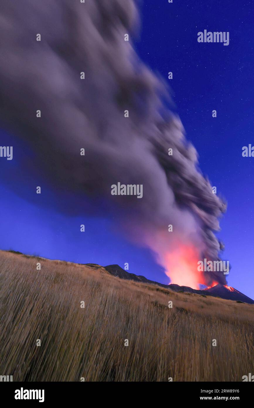 Eruzione del vulcano Etna visto all'alba con grandi emissioni di cenere dal cratere con cielo azzurro  nello sfondo; 13 Agosto 2023 Stock Photo
