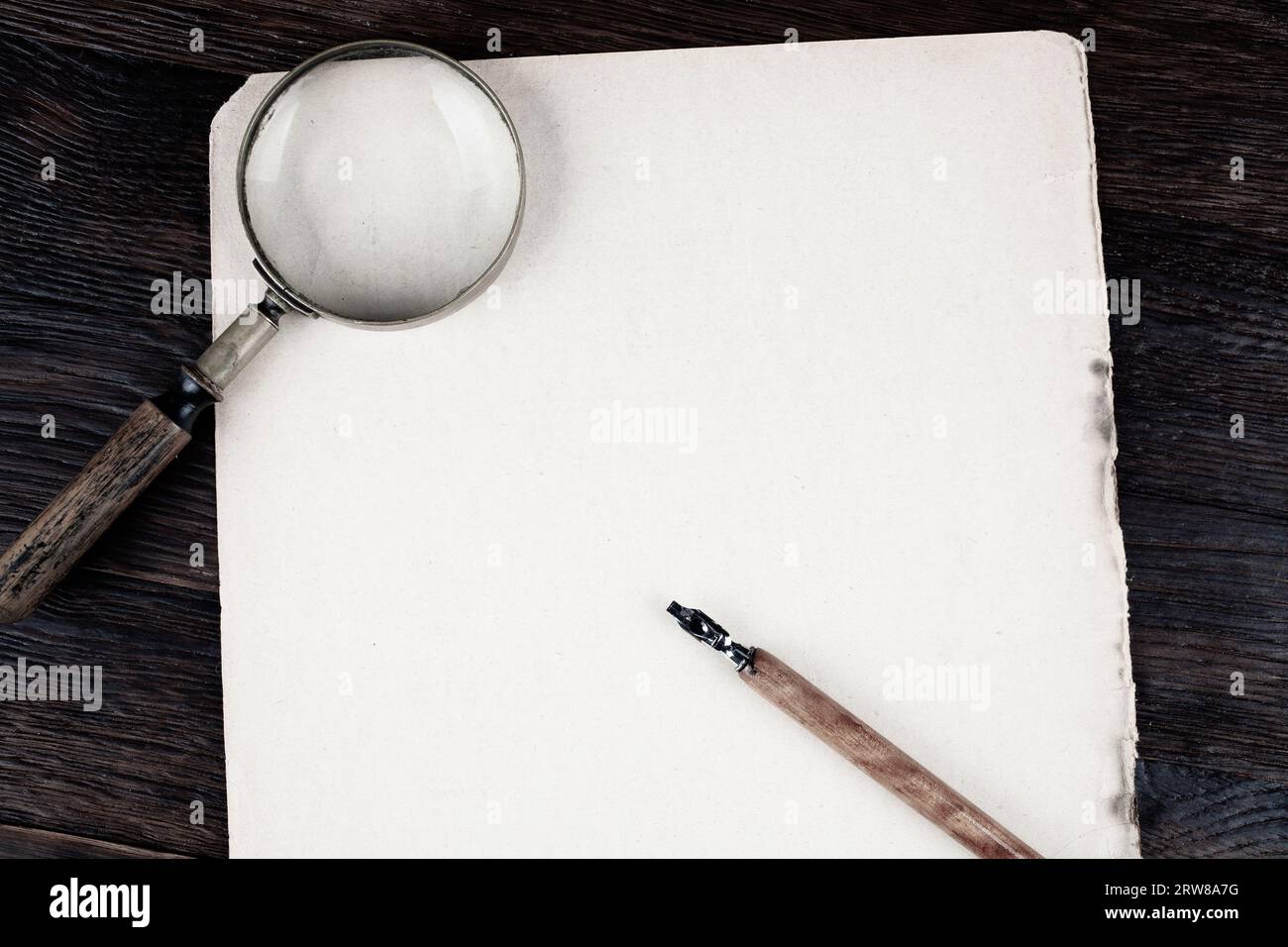 Magnifying glass with old ink feather pen on paper background Stock ...