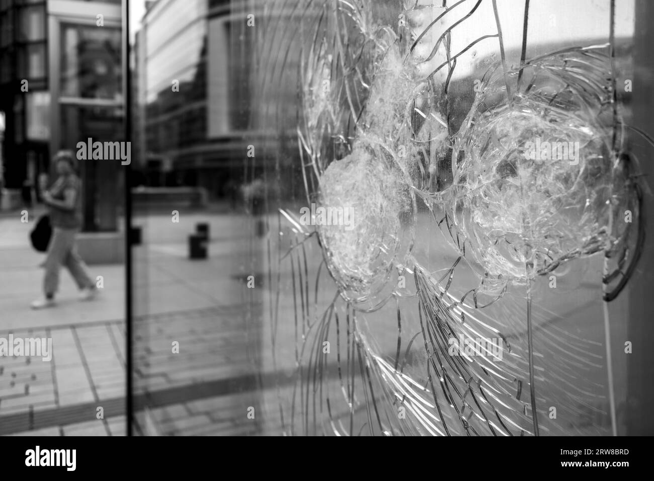 Black and white tone, blur city sidewalk and the street reflection on broken crack glass window. Stock Photo