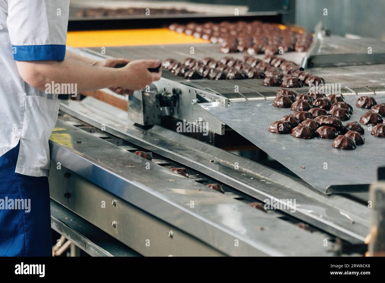 Confectionery worker sorting marshmallows on conveyor belt Stock Photo
