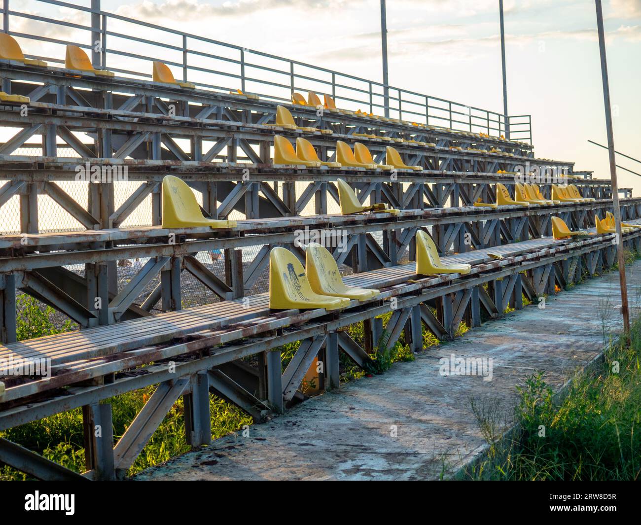 Old broken plastic chairs at the stadium. Abandoned stand at the stadium. Concept of devastation. There are no fans. Stock Photo