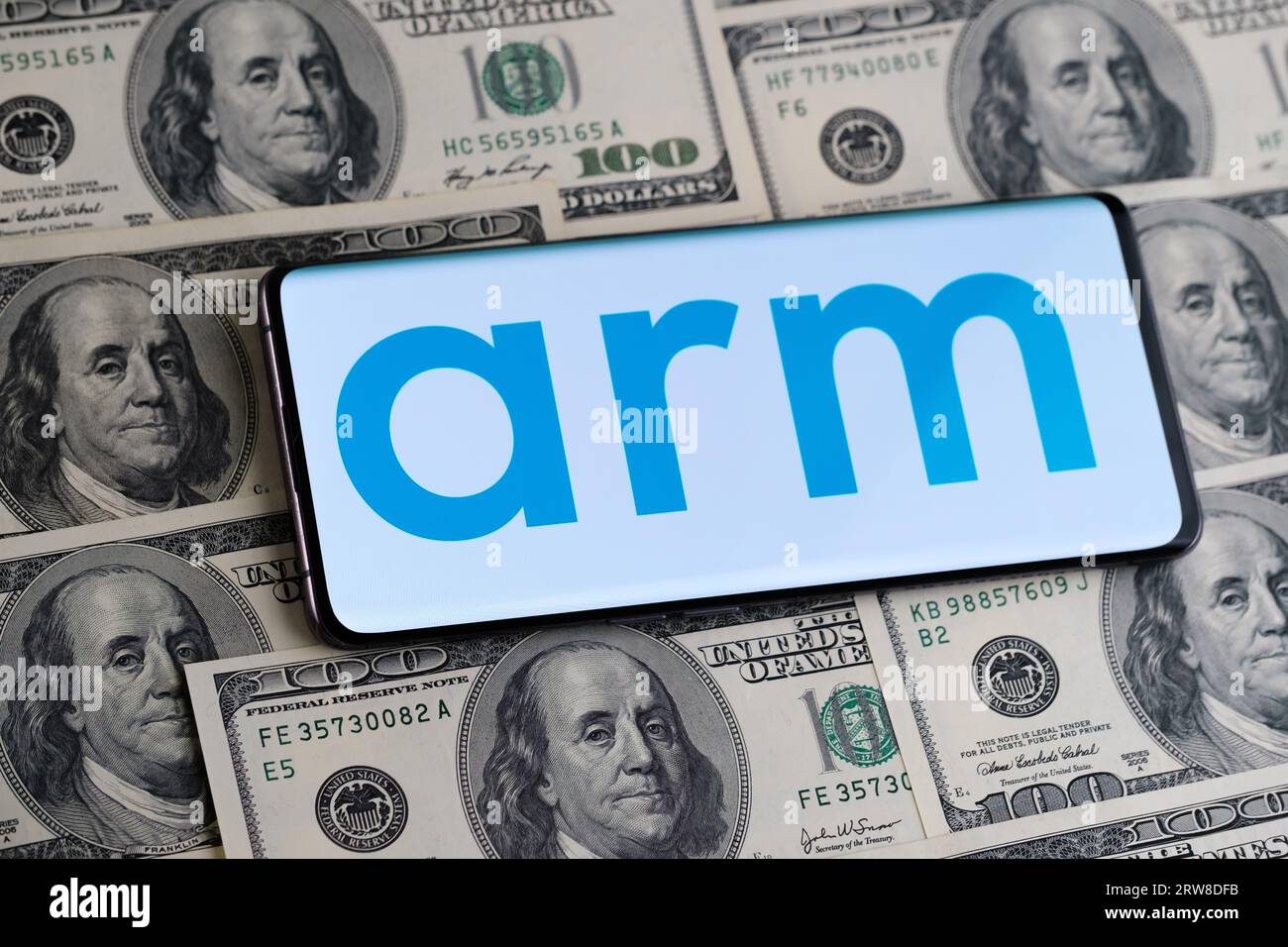 ARM logo seen on smartphone which is placed on hundred dollar bills. Concept for ARM company IPO and profits. London, United Kingdom, September 17, 20 Stock Photo