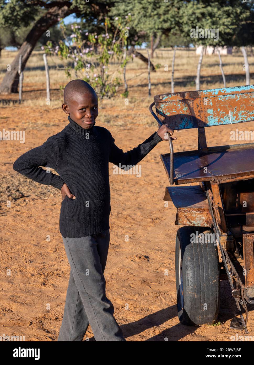 young village african boy holding the handle of artisanal hand made cart pulled by animals Stock Photo
