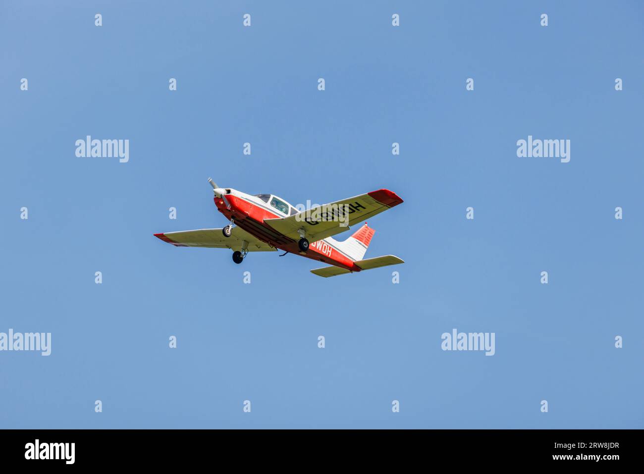 A red and white Piper PA-28-161 Cadet light aircraft in flight, climbing after take-off from Fairoaks Airport, Chobham, Surrey Stock Photo
