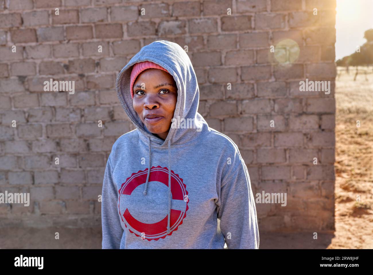 african girl with a hoodie, standing in the yard at sunset, village in africa Stock Photo