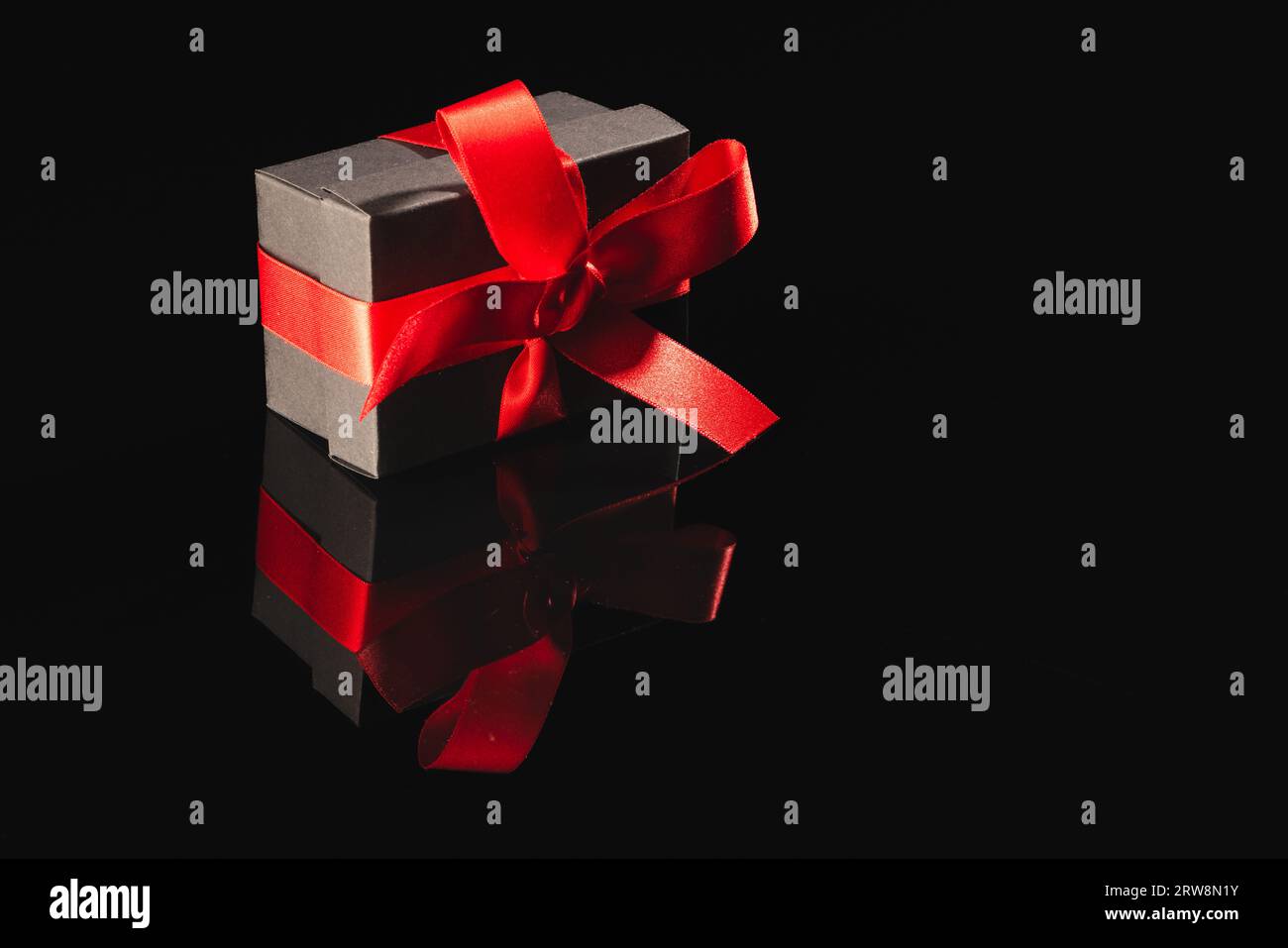 Black gift box with ribbon and copy space over black background Stock ...