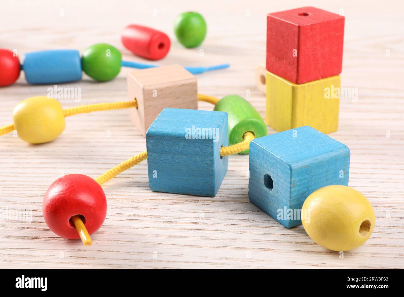 Wooden pieces and string for threading activity on light table, closeup