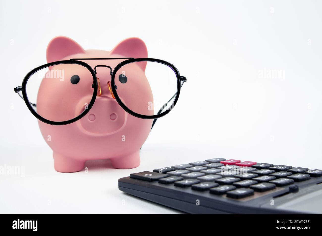 Glasses piggy bank with calculator on white background Stock Photo - Alamy