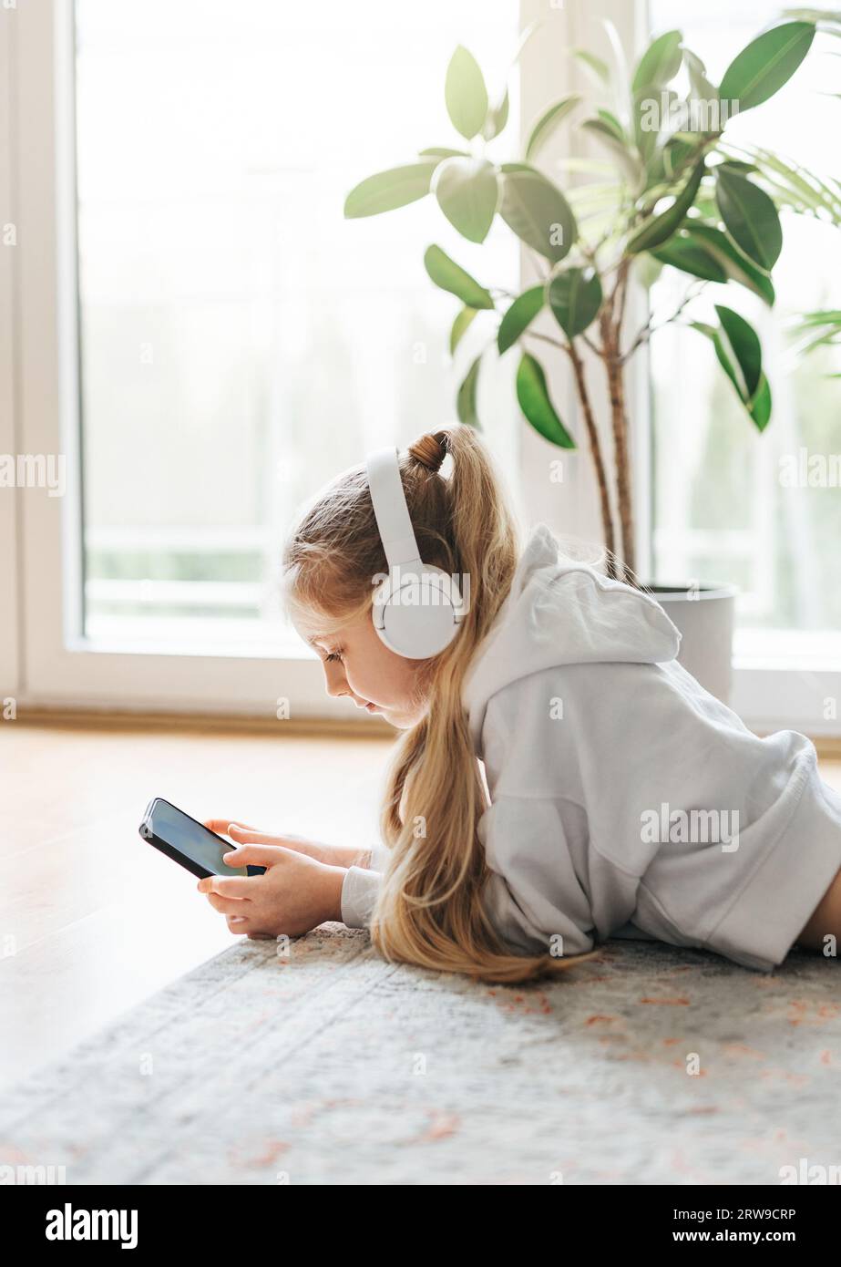 Smiling little girl listening music lying on the floor Stock Photo - Alamy