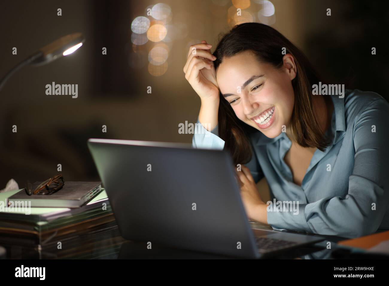 Happy busineswoman laughing in the night using laptop at home Stock Photo