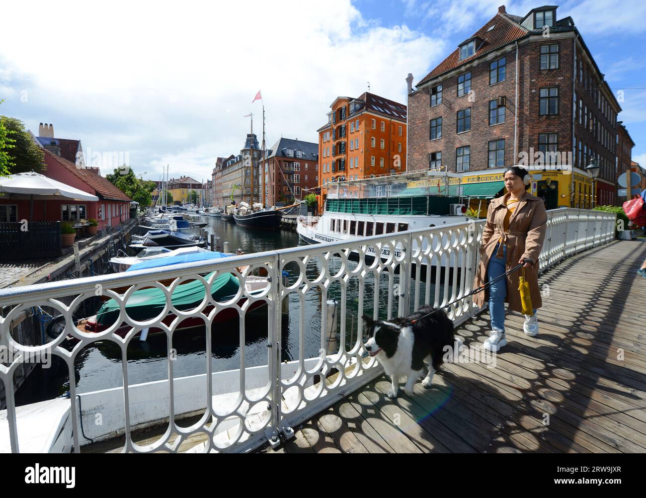 A woman and her pet dog crossing a bridge over the Christianshavn canal in Copenhagen, Denmark. Stock Photo