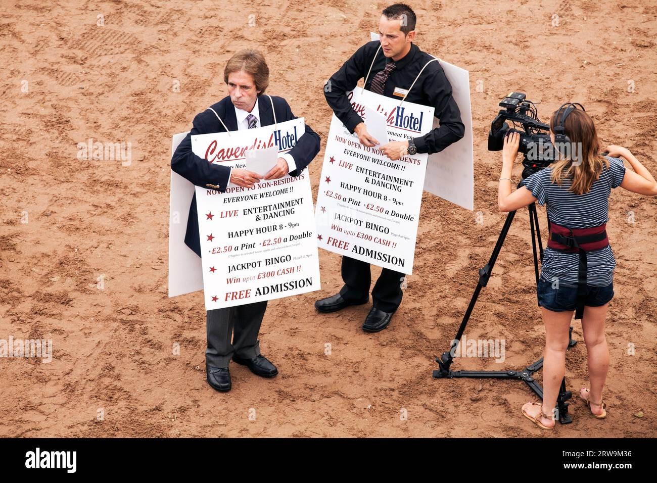 Mark Jenkins filming series 4 of The Hotel on Torquay seafront beach with sandwich boards 2014 Stock Photo