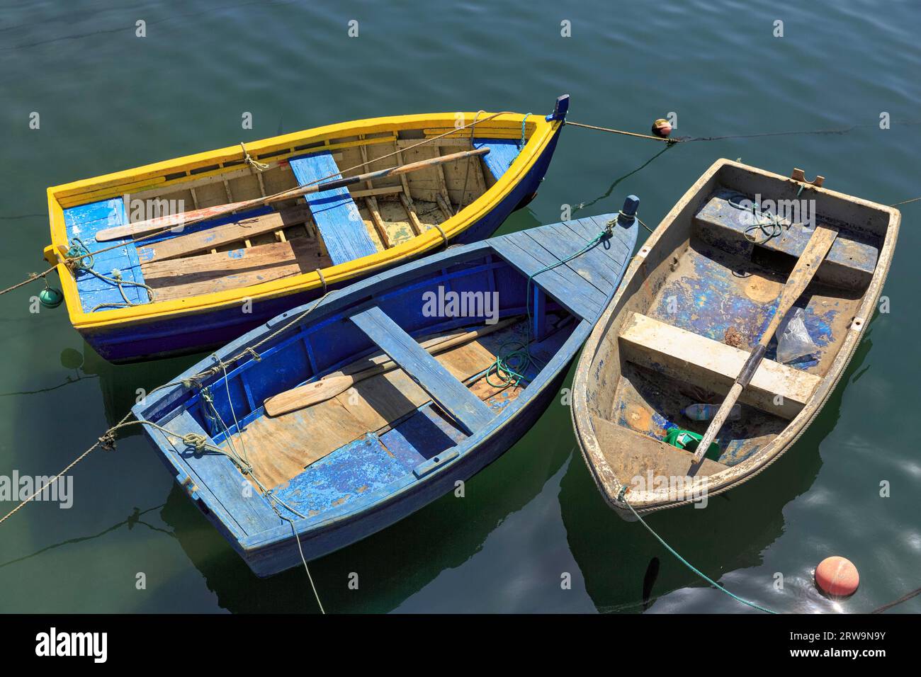 Three rowing boats side by side in the harbour, plastic waste, plastic bottles, Porto Covo, Portugal Stock Photo