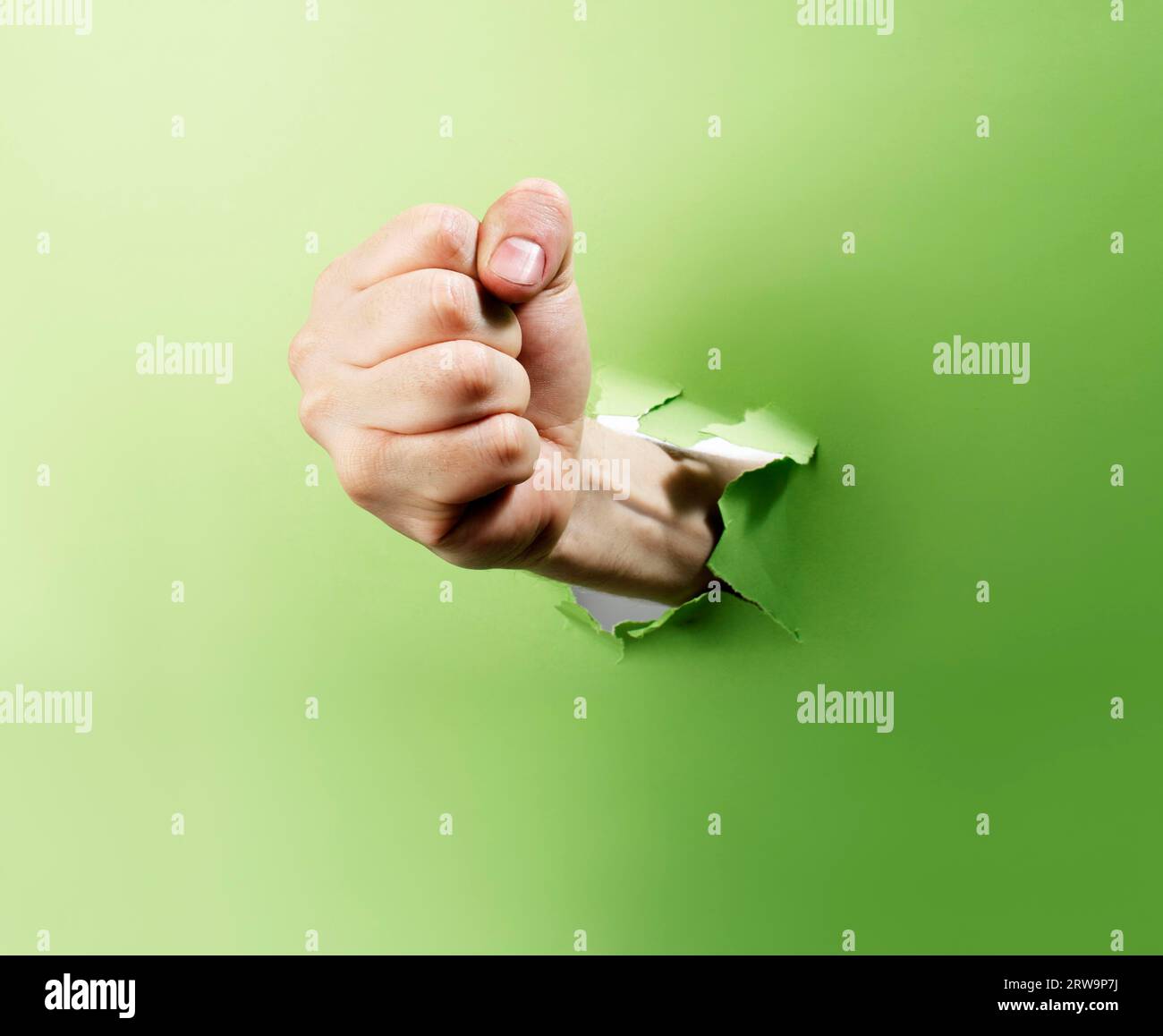 Man punching through green paper with his fist Stock Photo Alamy