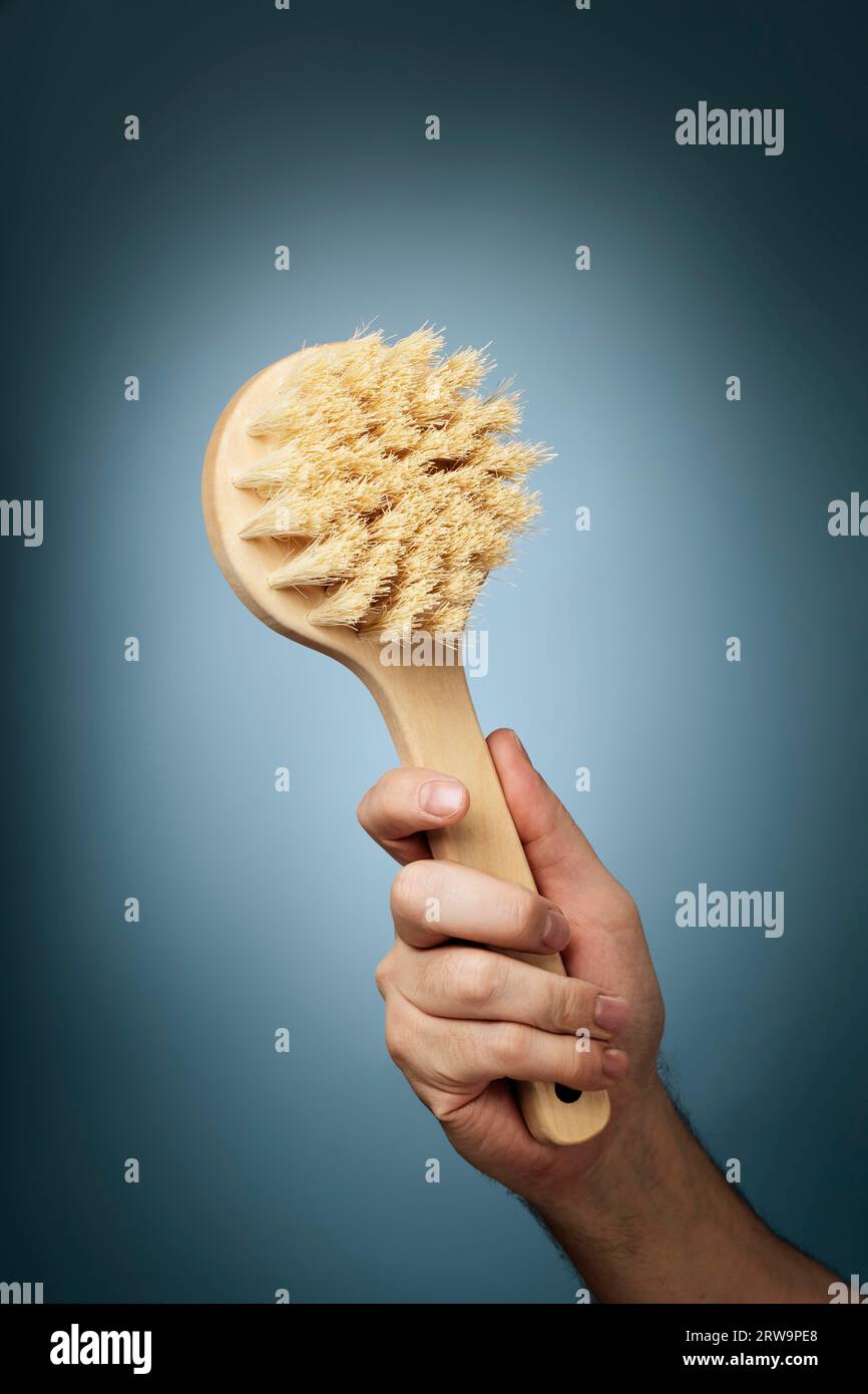 Man holding a brush made of wood and natural fibers in his hand Stock Photo