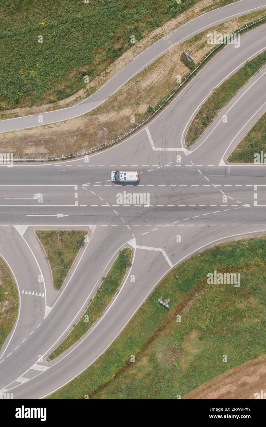 Aerial shot of ambulance van on road intersection, drone pov directly above Stock Photo