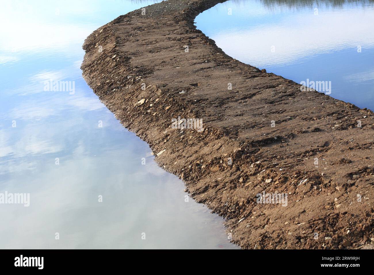 Path into a pond, water with sky reflections Stock Photo