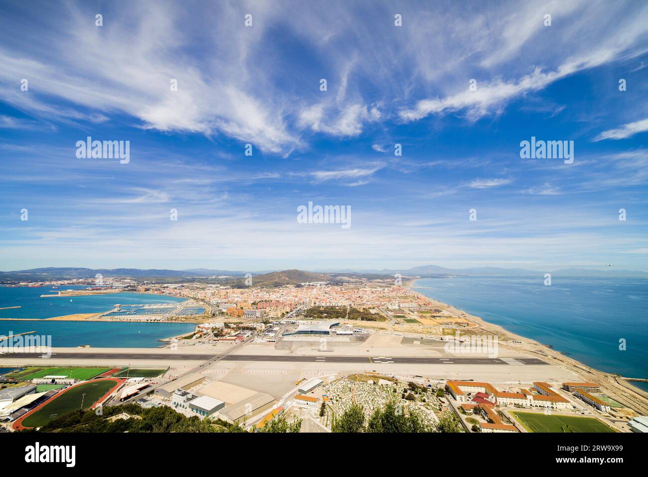Gibraltar airport runway, La Linea de la Concepcion town in Spain at the far end, Mediterranean Sea on the right, Gibraltar Bay on the left and sky Stock Photo