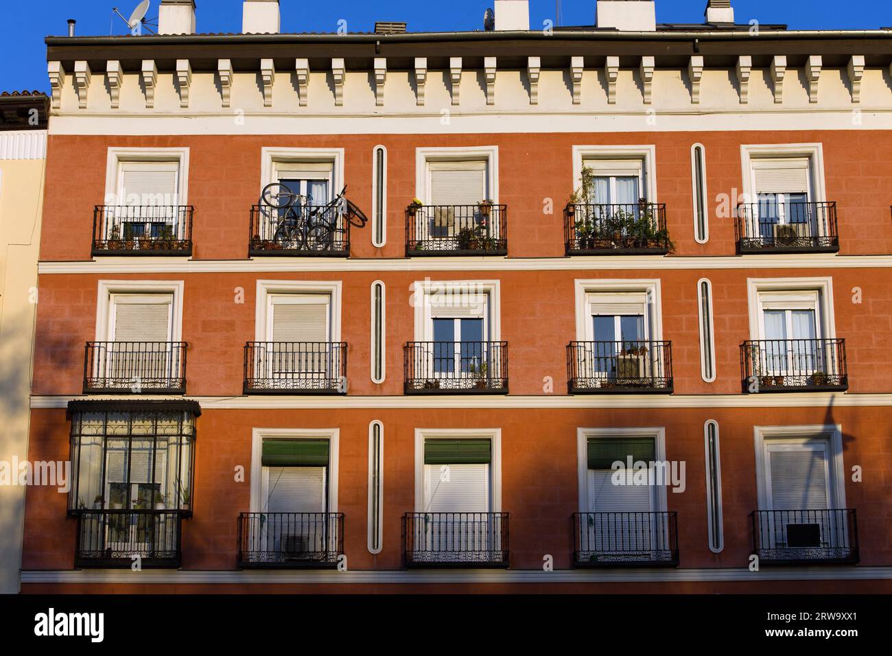 Red facade of traditional tenement house in Madrid, Spain Stock Photo