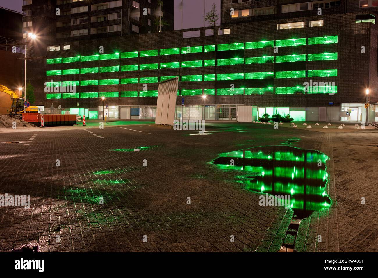 Urban abstract, green lights of a multi storey car park with reflections on water after the rain at night in Rotterdam, Netherlands Stock Photo