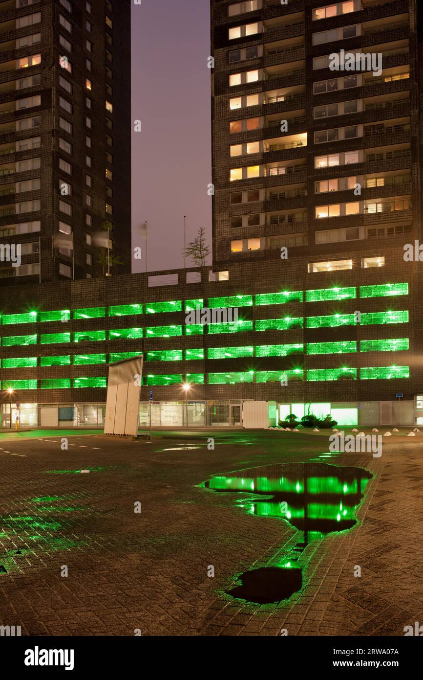 Green lights of a multi storey car park with reflections on water after ...