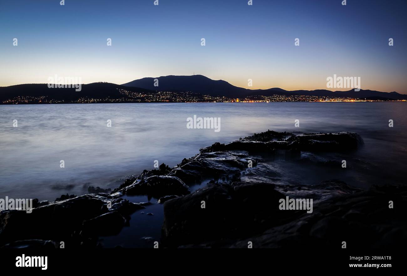 View from Tranmere on the River Derwent with illuminated Hobart, Tasmania with Mount Wellington in background Stock Photo