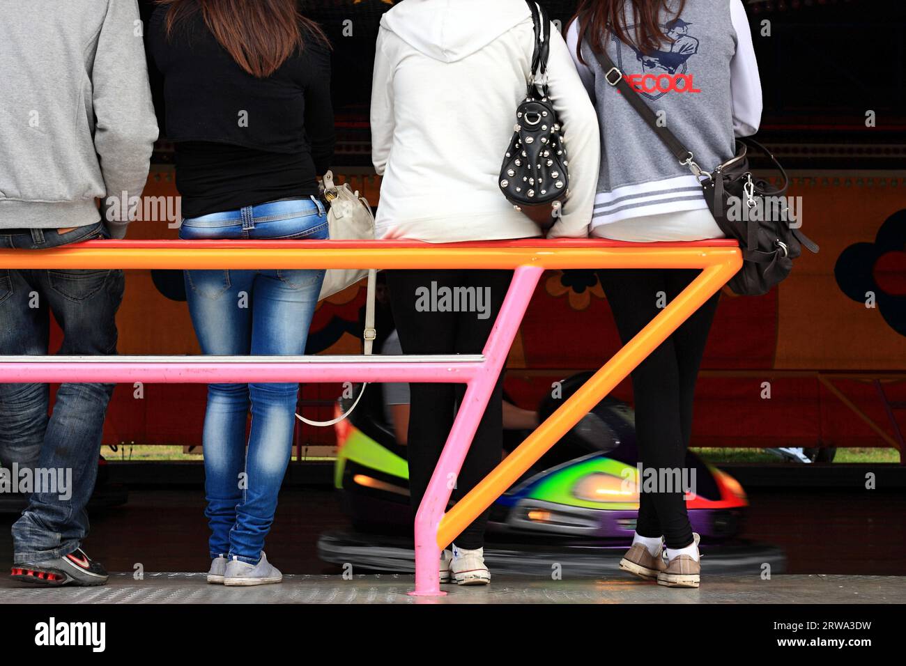 Four teenagers waiting at a perch near a bumper car, background, ride ...