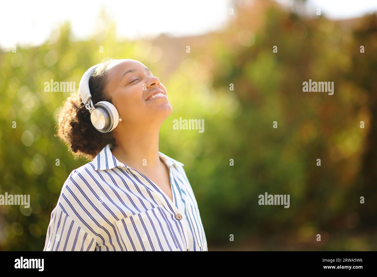 Happy black woman meditating listening audio guide with headphone in a park Stock Photo